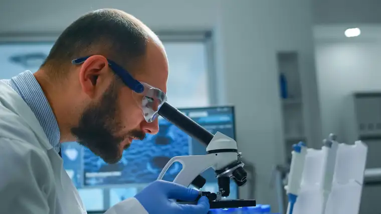 Cientista analisando amostras ao microscópio em laboratório