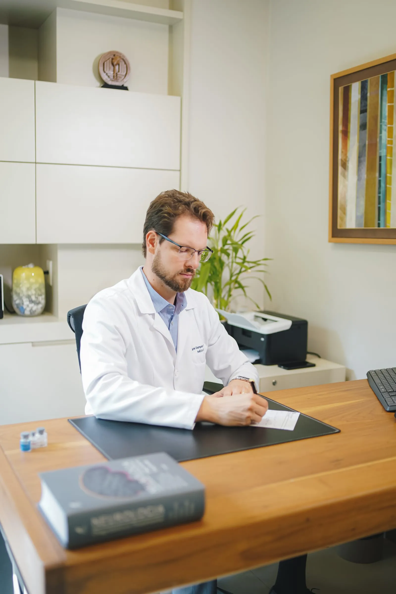 Dr. Gabriel Sampaio Froehner escrevendo uma prescrição no consultório