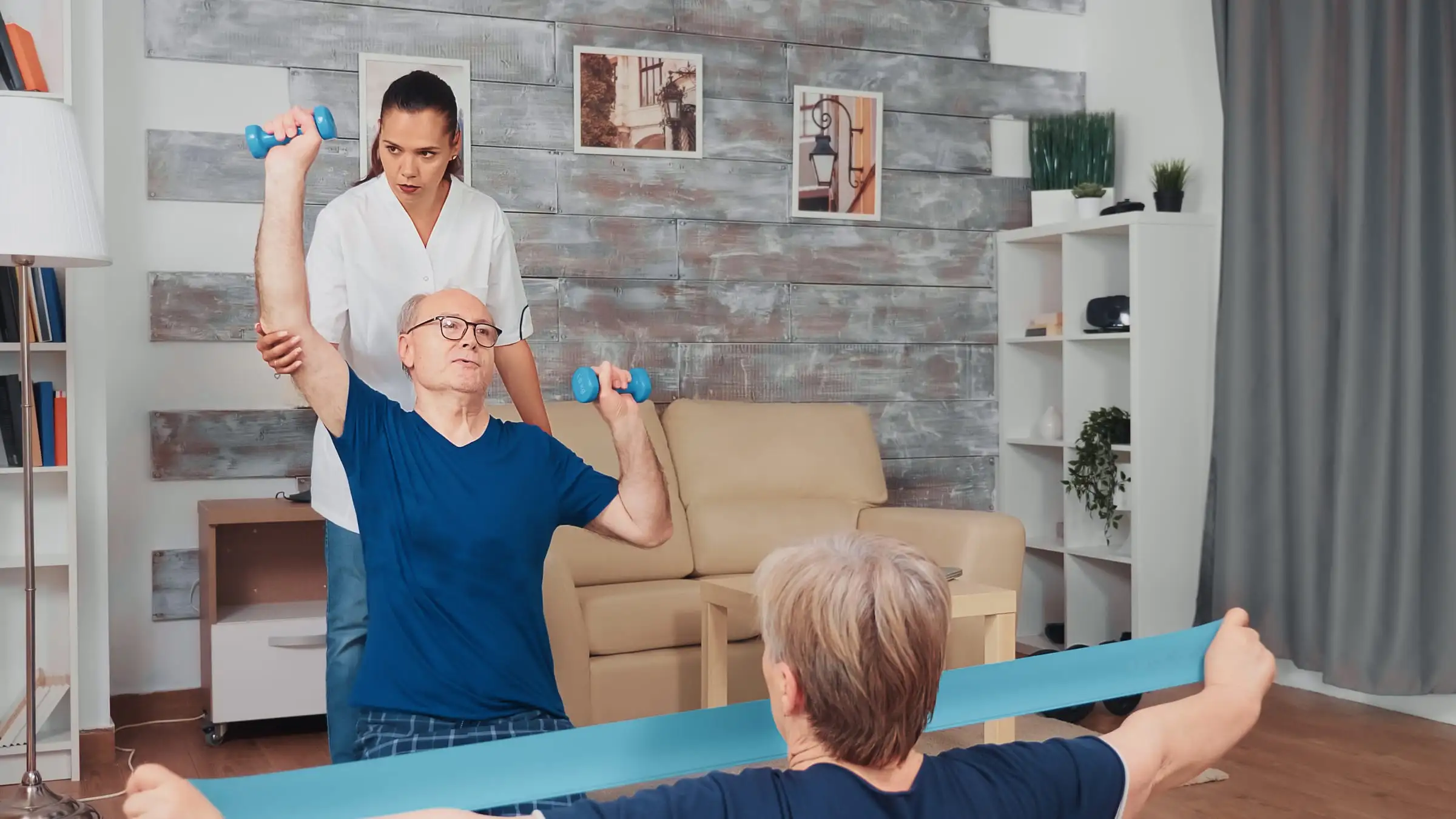 Profissional de reabilitação orientando exercícios para casal idoso em casa