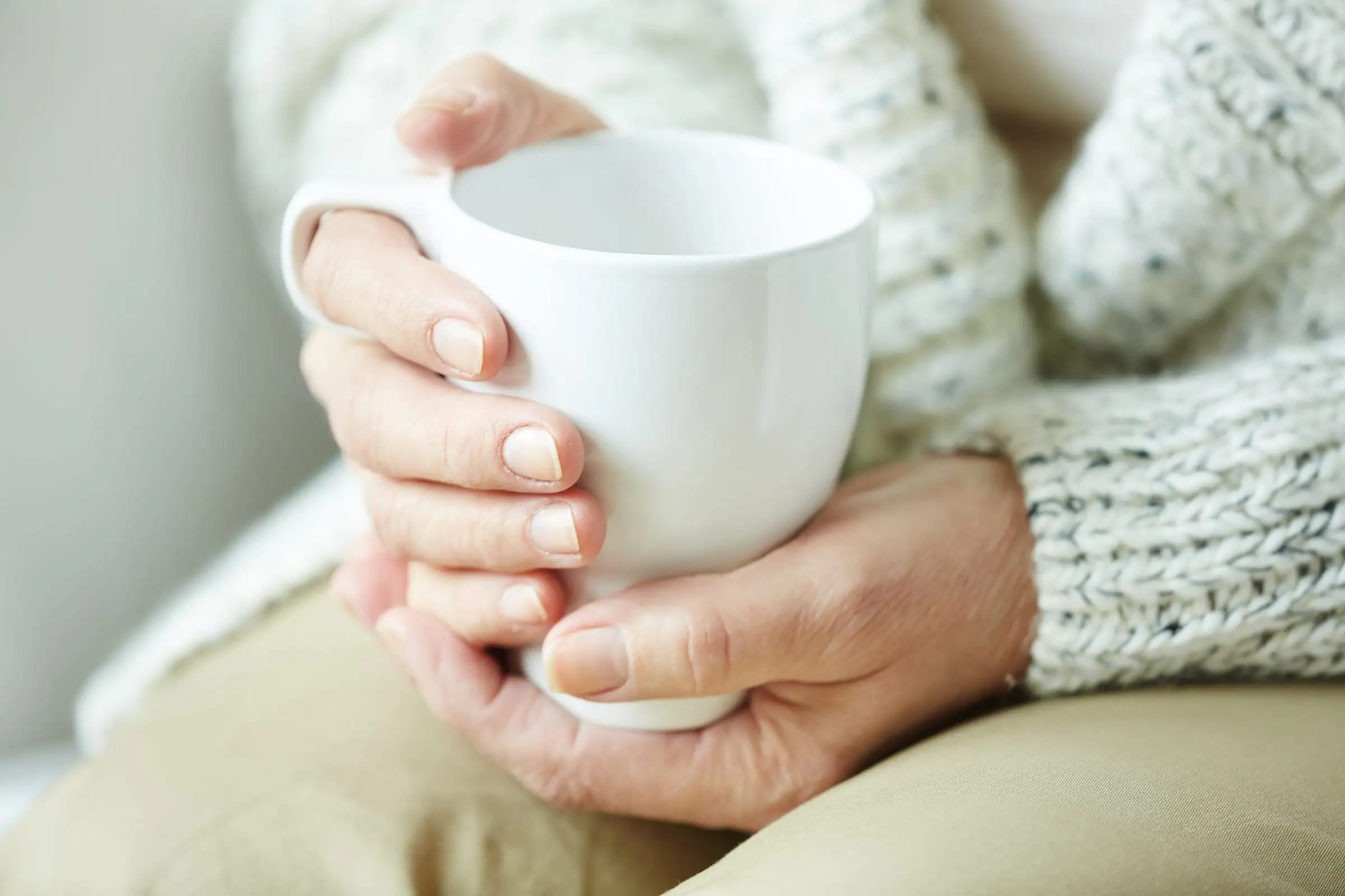 Mãos de pessoa idosa segurando uma xícara de café