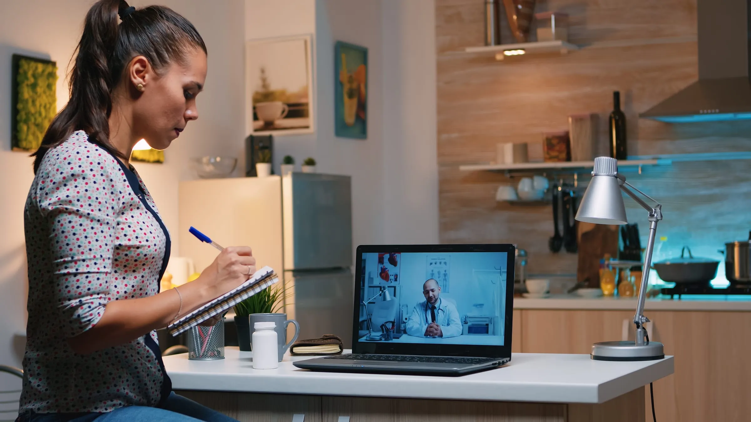 Mulher em casa fazendo anotações durante uma consulta por vídeo no notebook