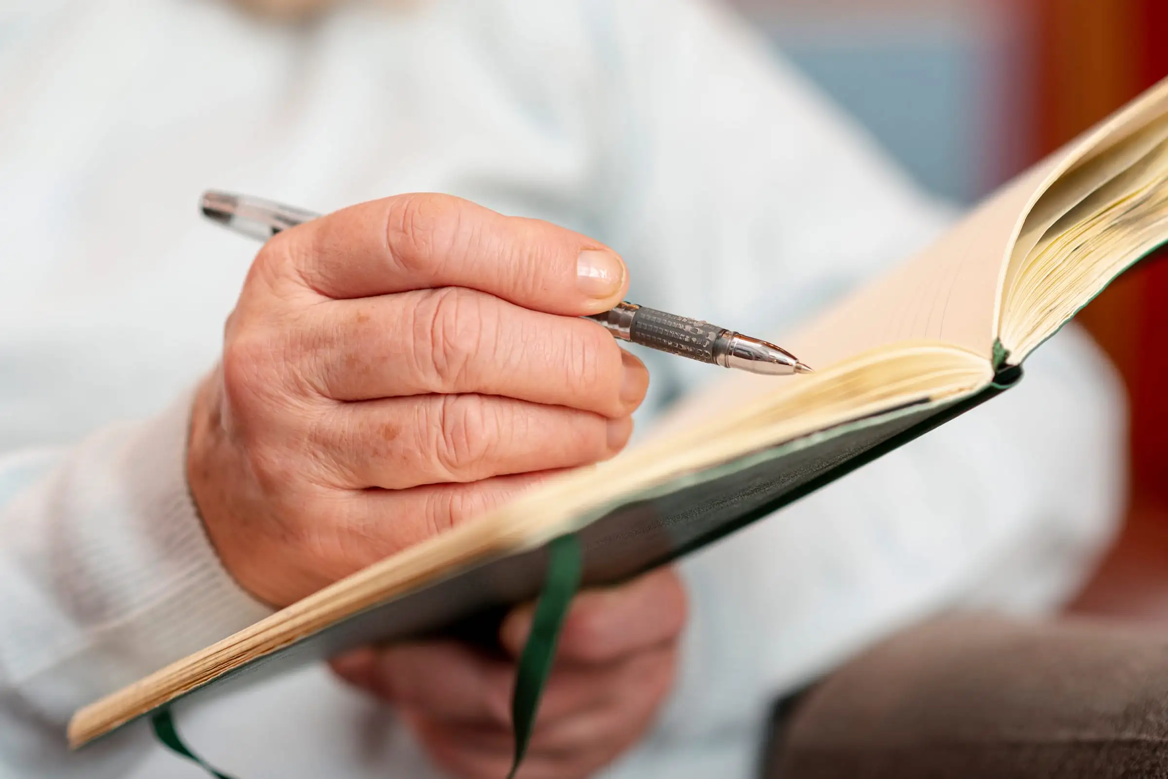 Mãos de senhora fazendo anotações em um caderno
